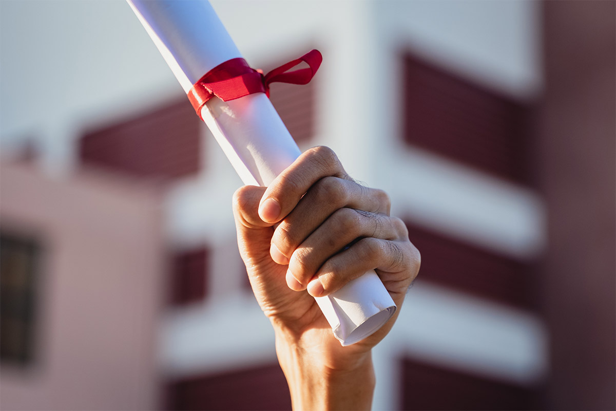 a college graduate holds his degree in the air